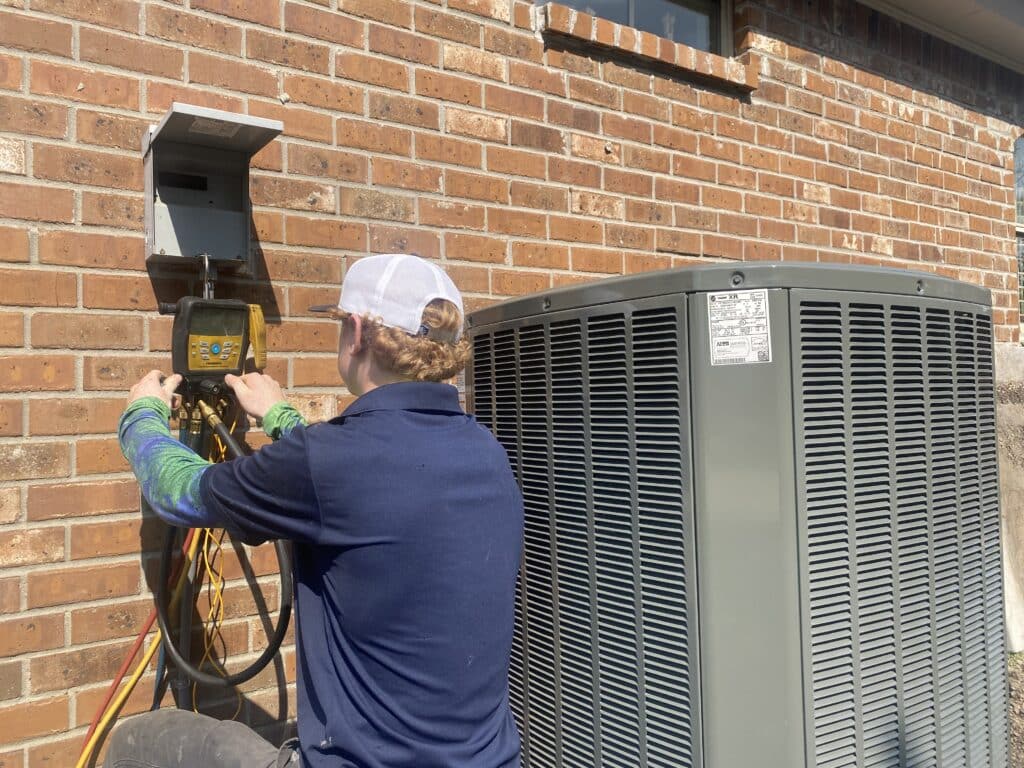 ac tech performing ac maintenance on an hvac unit