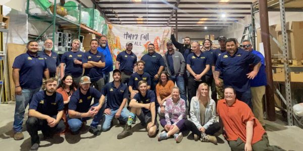 Large group of Southern Air HVAC and electrical team members posing together in a warehouse setting with a Happy Fall Y'all banner.